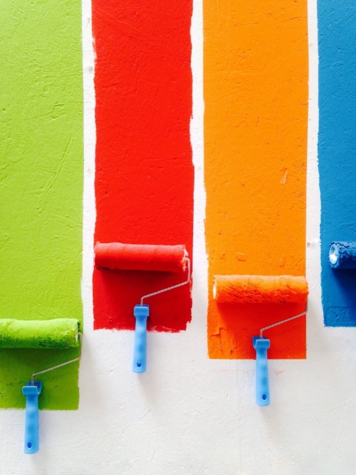 Four paint rollers in orange, green, blue, and red, symbolizing vibrant color choices