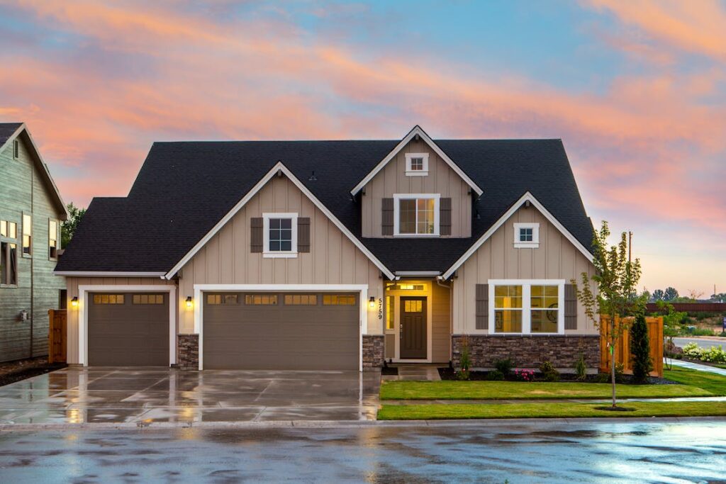An image of a house with a dark grey roof, beige walks, and brown garage doors