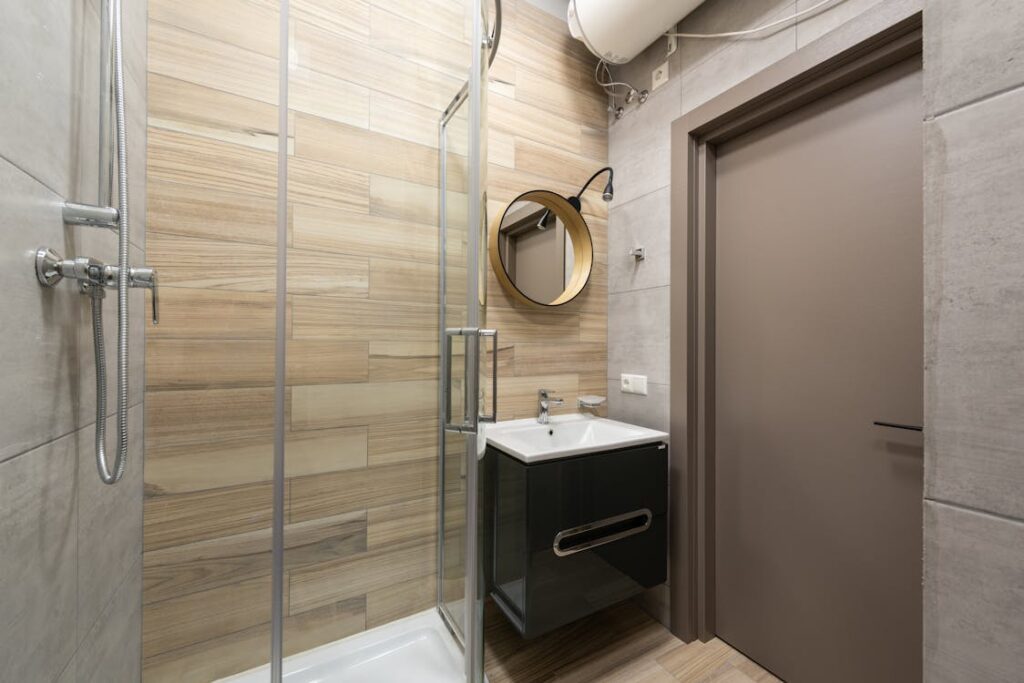 An image of a small bathroom with a sink, mirror, and shower
