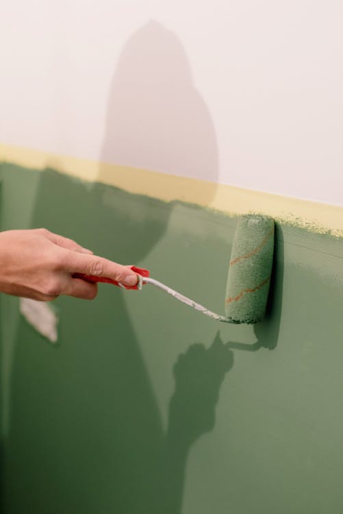 An image of a hand painting a wall green in an apartment